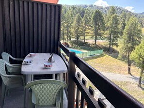 Ein Balkon mit Tisch, Stühlen und Blick auf eine bewaldete Landschaft.