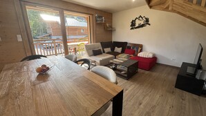 A wooden interior with a dining table, sofa, and a staircase. - Contemporary apartment - 8 guests (Les Carroz d'Arâches)