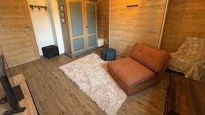 A room with a wooden wardrobe, a sofa, a rug, and a small ottoman. - Contemporary apartment - 8 guests (Les Carroz d'Arâches)