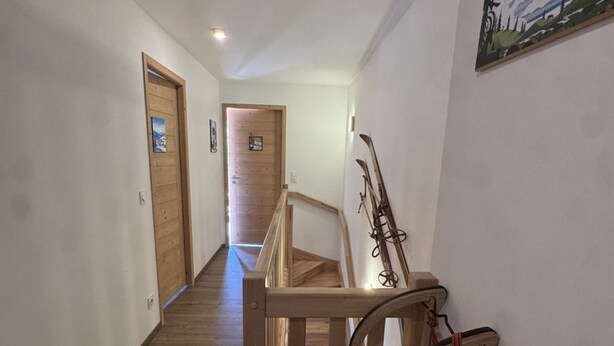 A hallway with wooden flooring, wooden doors, and a ski rack against the wall. - Contemporary apartment - 8 guests (Les Carroz d'Arâches)