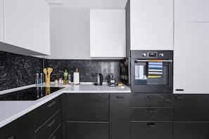 A modern kitchen with black cabinets, a white countertop, and a built-in oven. - Warsaw Center Apt — Old Town Nearby, Workspace (Warszawa)