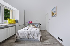 Ein Schlafzimmer mit Bett, Fenster, Heizkörper und einem Bild an der Wand.