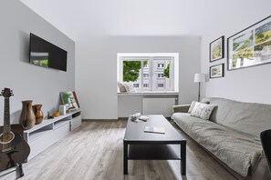 Een moderne woonkamer met een bank, salontafel en een raam met uitzicht op gebouwen.