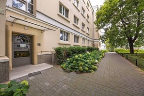 A building with a flat facade, a gated entrance, and a paved pathway lined with greenery. - Warsaw Center Apt — Old Town Nearby, Workspace (Warszawa)
