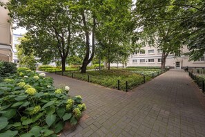 A paved walkway lined with trees and greenery, leading to a building with multiple windows. - Warsaw Center Apt — Old Town Nearby, Workspace (Warszawa)
