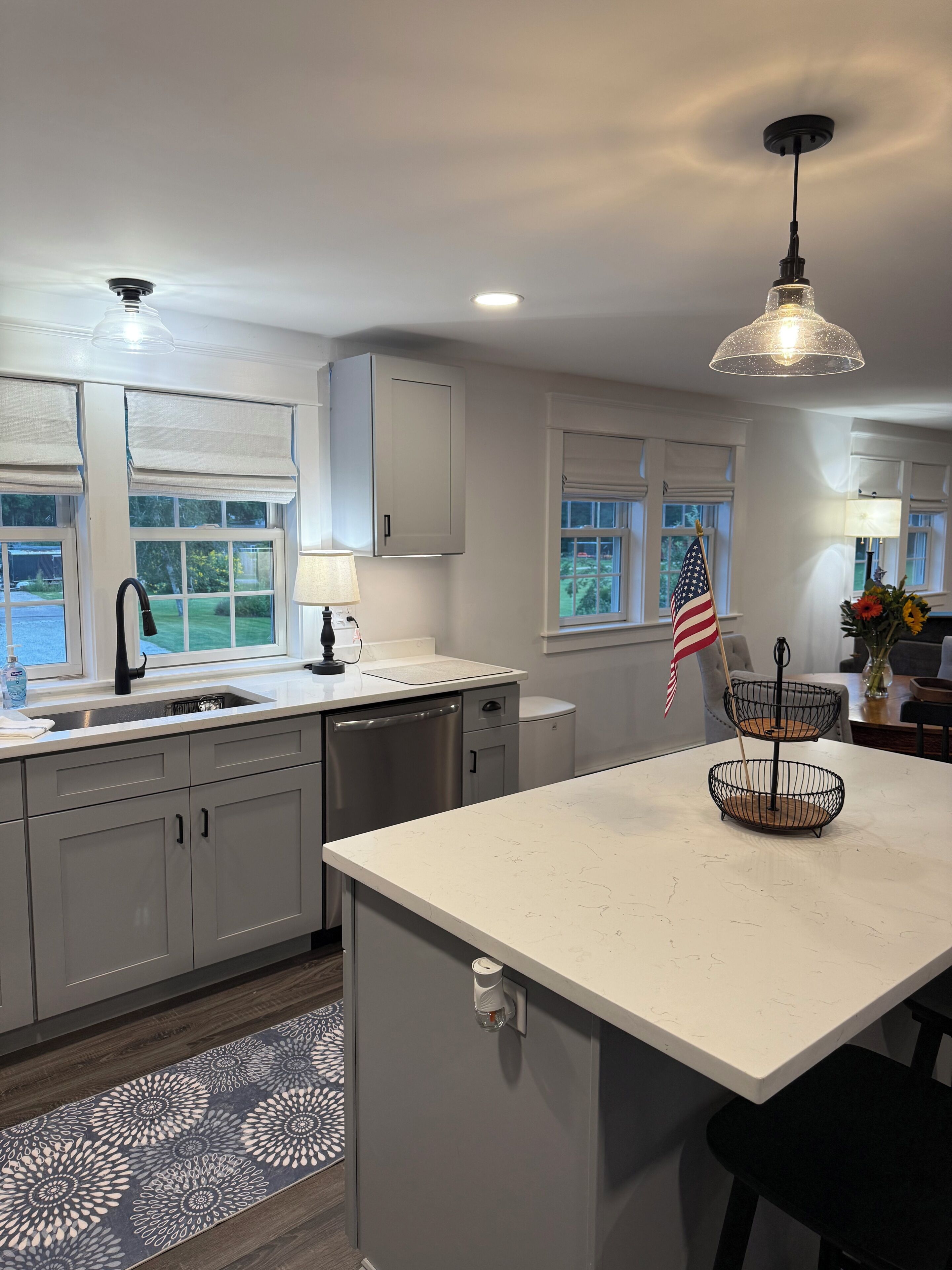 A modern kitchen with a central island, a sink with a faucet, and a window with a view of greenery.