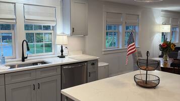 A modern kitchen with a central island, a sink with a faucet, and a window with a view of greenery.