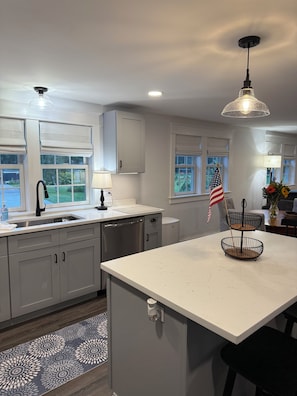 A modern kitchen with a central island, a sink with a faucet, and a window with a view of greenery.