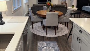 A modern kitchen with a dining area, a flat-screen TV, and a sofa.