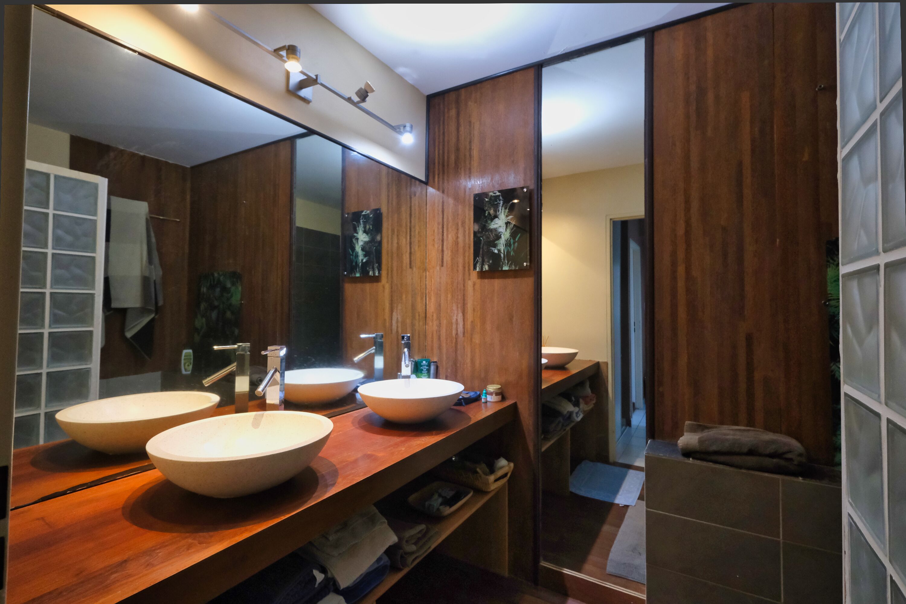 Un baño moderno con dos lavamanos grandes, un espejo y paneles de madera.