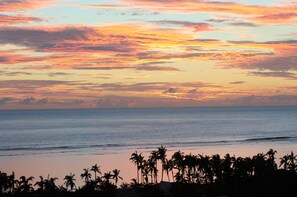 A beach with palm trees and a sunset. - Charming 100-square-meter apartment + 40-square-meter terrace with a stunning view of the sea and lagoon (Saint-Paul)