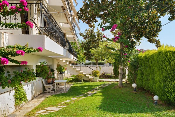 A residential building with a garden, outdoor furniture, and a staircase leading to the entrance.