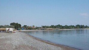Ein Strand mit Kiesufer, einigen Zelten und einem ruhigen Gewässer.