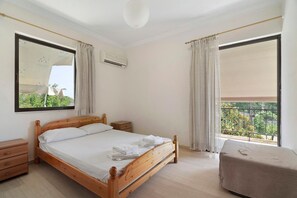 Ein Schlafzimmer mit einem hölzernen Bett, einem Nachttisch, einem kleinen Holztisch, einer Deckenleuchte und einem Fenster mit Vorhängen.