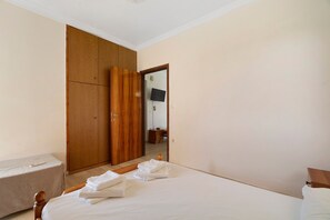 Ein Schlafzimmer mit einem Bett, einem Holzschrank und einem Spiegel, der einen Fernseher und eine Kommode reflektiert.