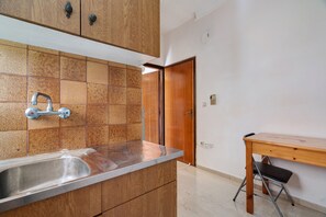 A kitchen with a sink, wooden cabinets, and a tiled backsplash. - Rousetis Studio 103 - 200m from the Sea in Aígio (Aigialeia)