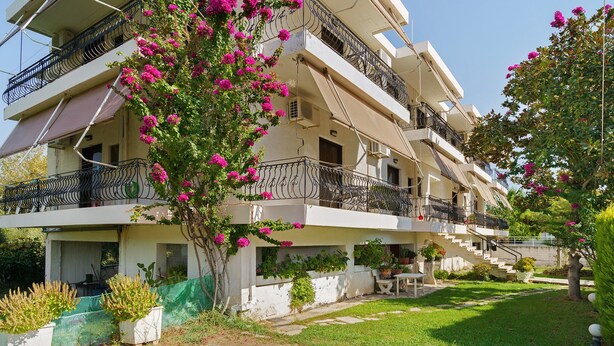 Un edificio residencial de varios pisos con balcones, un jardín y una escalera que conduce a los pisos superiores.
