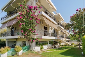 Um edifício residencial com vários andares, varandas, área de jardim e escada que dá acesso aos pisos superiores.