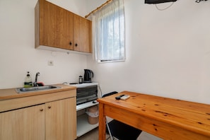 A compact kitchen with wooden cabinets, a sink, a kettle, and a small table. - Rousetis Studio 104 - 200m from the Sea in Aígio (Aigialeia)
