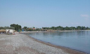 Ein Strand mit Kiesufer, einigen Zelten und einem ruhigen Gewässer.