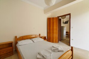 A bedroom with a wooden bed, a nightstand, a wooden wardrobe, and a mirror. - Rousetis Two-Bedroom Apt 203 - 200m from the Sea (Aigialeia)