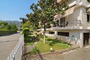 A residential building with a balcony, a paved driveway, and a clear sky. - Rousetis Studio 106 - 200m from the Sea in Aígio (Aigialeia)