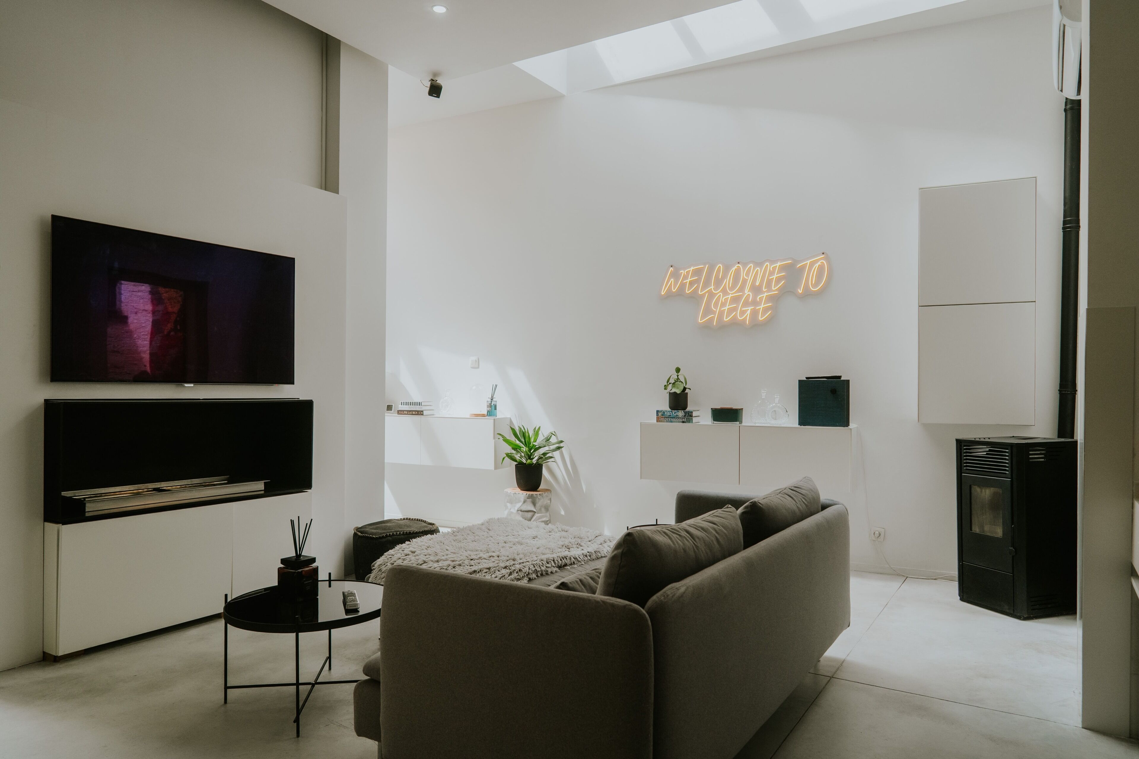 Ein modernes Wohnzimmer mit Flachbildfernseher, einer Couch, einem Couchtisch und einem Kamin.