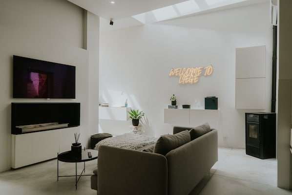 A modern living room with a flat-screen TV, a sofa, a coffee table, and a fireplace.