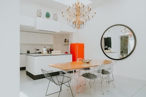 A modern kitchen with white cabinetry, a central island, and a dining area with a round table and chairs.