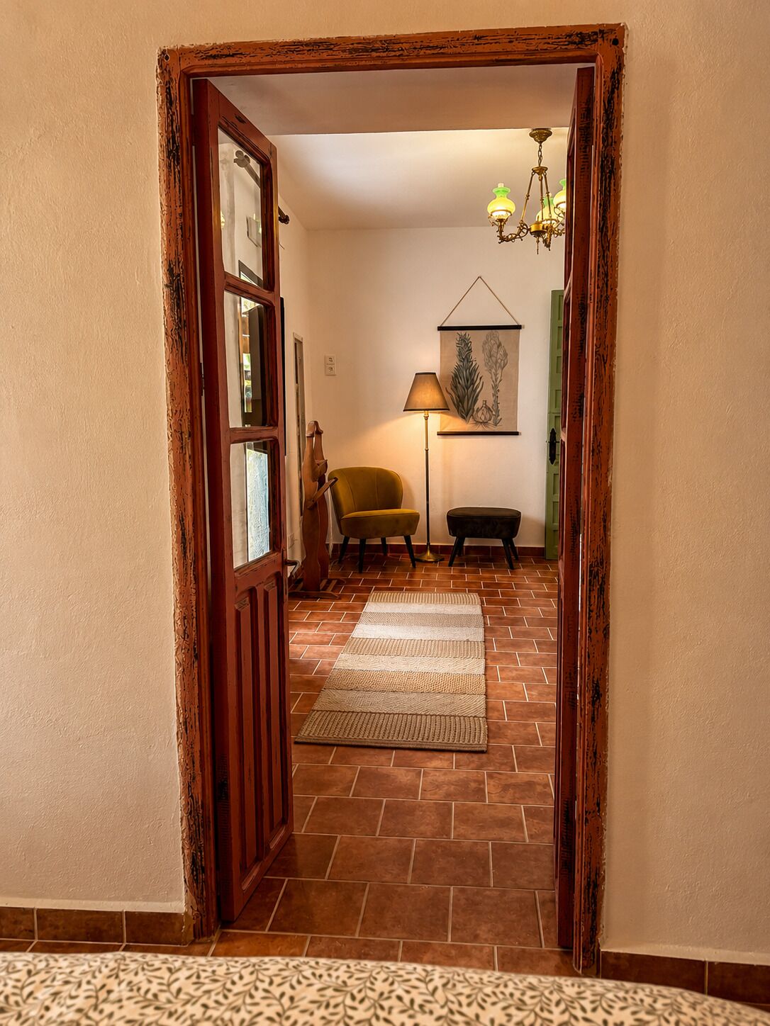 Un couloir avec une porte en bois, une lampe, une chaise et un tapis.