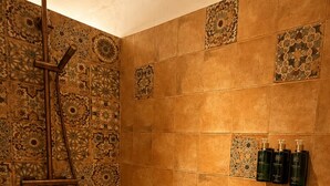 Un bagno con doccia, piastrelle decorate e articoli da toilette a parete.