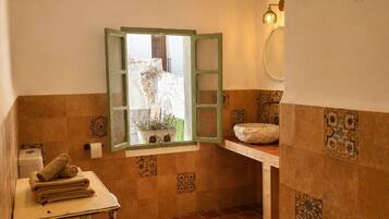 Un baño con ventana, lavamanos y toallero.
