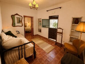 Une chambre à coucher avec un lit, une chaise, une lampe, un miroir, une porte et une fenêtre.