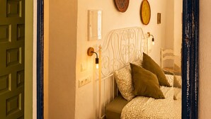 Ein Schlafzimmer mit einem Bett, Nachttisch und einem Spiegel mit dekorativen Tellern an der Wand.