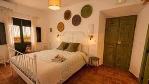 Ein Schlafzimmer mit einem Bett, Nachttischlampen, einer grünen Tür und einer Wand mit dekorativen Tellern.