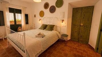 A bedroom with a bed, bedside lamps, a green door, and a wall with decorative plates.