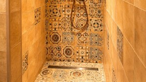 Eine Dusche mit Handbrause und Wand mit aufwendigen Fliesenmustern.