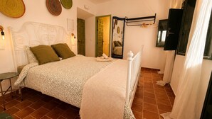 Ein Schlafzimmer mit Bett, Nachttisch, Pendelleuchte und Spiegel.