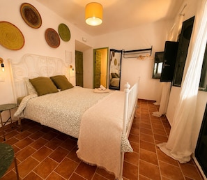 Une chambre à coucher comprenant un lit, une table de chevet, un luminaire suspendu et un miroir.