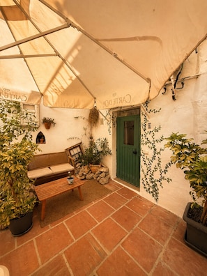 Zona d'estar a l'aire lliure coberta, amb una banca, taula i plantes en testos.