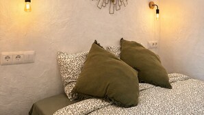 Une chambre à coucher avec un lit, deux lampes fixées au mur, un miroir rond et une prise de courant.