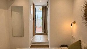 Une chambre d’hôtel comprenant un lit, un climatiseur fixé au mur, une porte donnant sur un balcon et un luminaire fixé au mur.