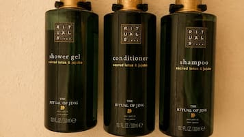 Trois flacons de produits de la gamme Ritual of Jing sont posés contre un mur.