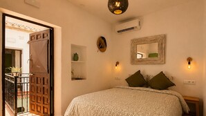 Ein Schlafzimmer mit einem Bett, einem Teppich, einer Tür und einer wandmontierten Lampe.