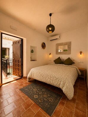 Une chambre à coucher avec un lit, un tapis, une porte et un luminaire fixé au mur.