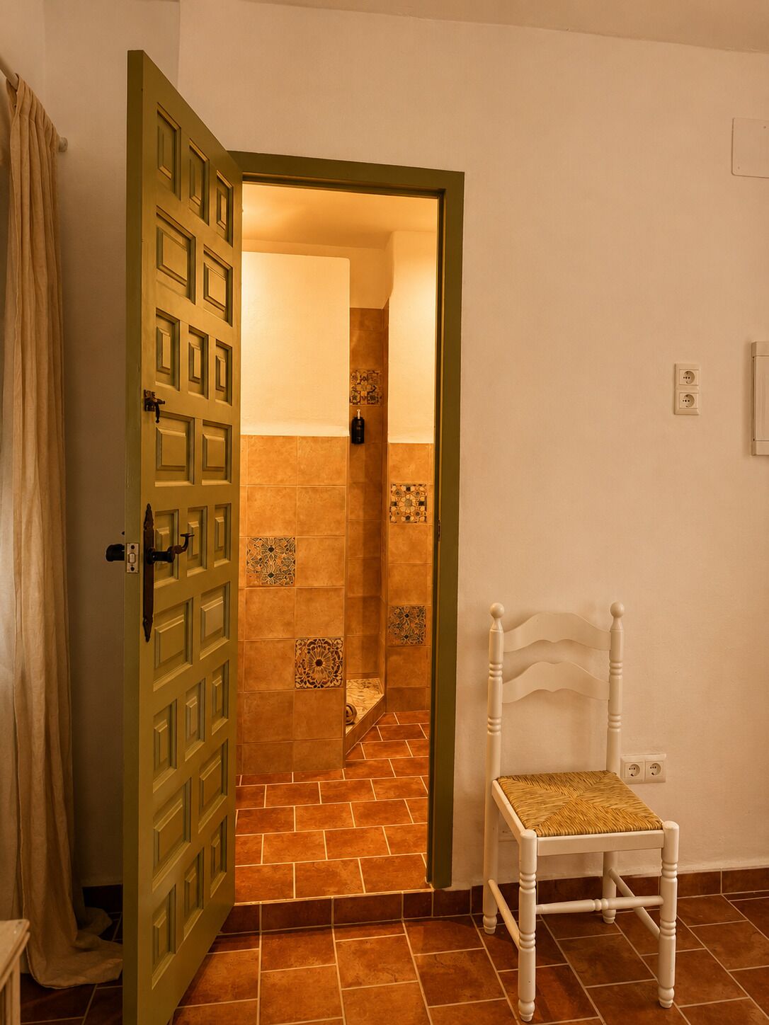 Une pièce avec une porte en bois, une chaise blanche et un sol carrelé.