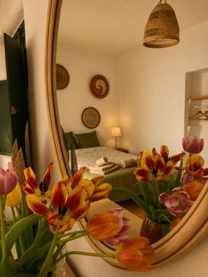 Un dormitorio con cama, espejo, lámpara colgante y un muro con dos platos decorativos.