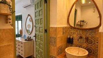 Un baño con una bañera independiente, un espejo grande y una puerta que da a otra habitación.