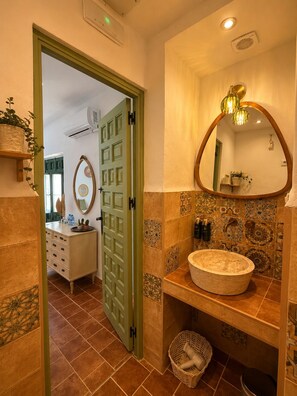 Un baño con una bañera independiente, un espejo grande y una puerta que da a otra habitación.