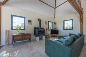 A living room with a fireplace, a sofa, a TV, and a window. - A charming home on the hills above Trouville (Trouville-sur-Mer)